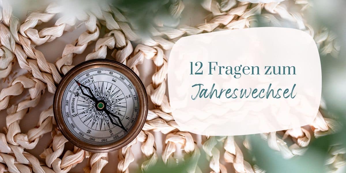 Kompass auf einer geflochtenen Unterlage, im Vordergrund verschwommene Blätter. Text: 12 Fragen zum Jahreswechsel